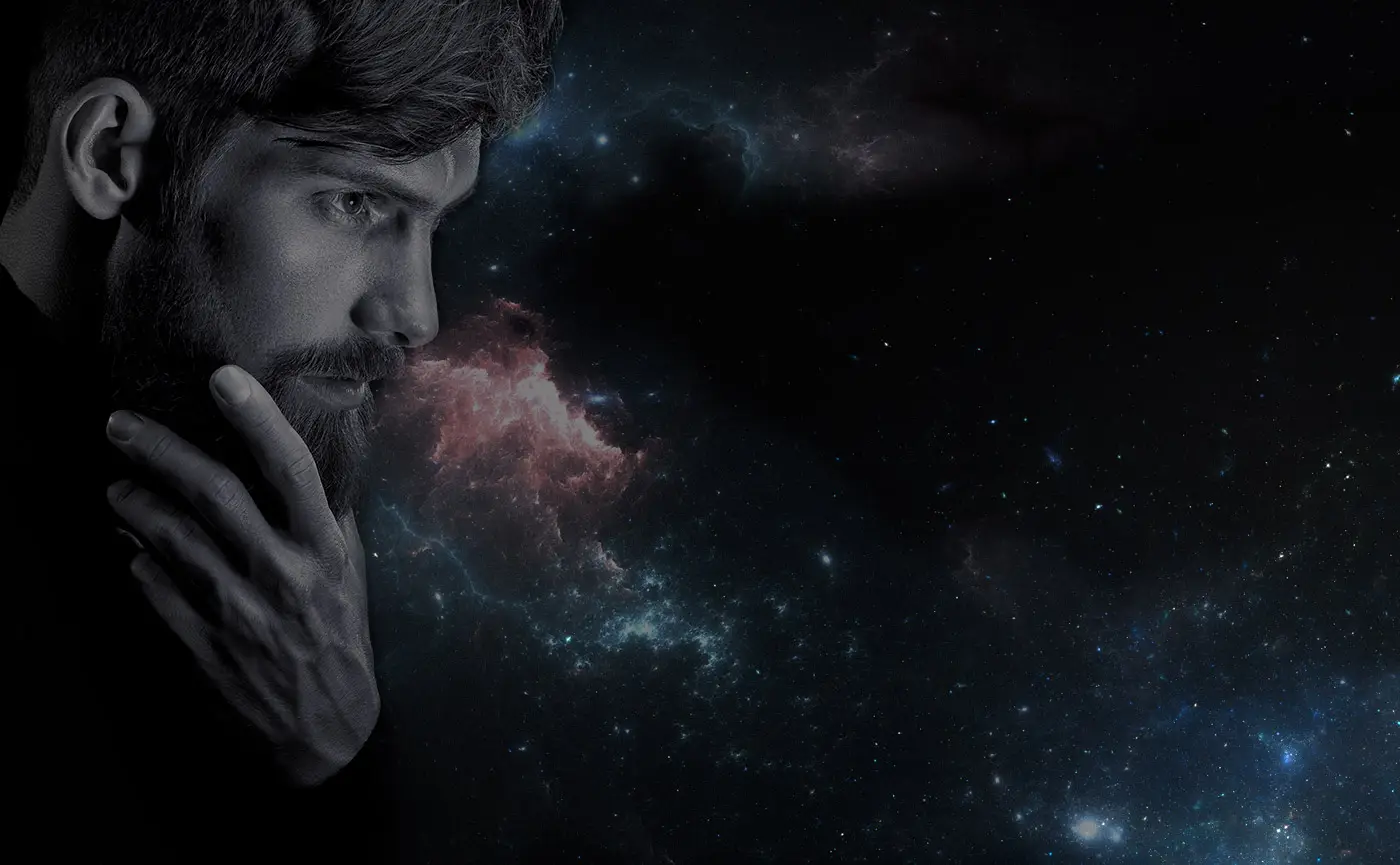 Profile view of a man with a beard and thoughtful expression against a cosmic backdrop with stars and nebulae.