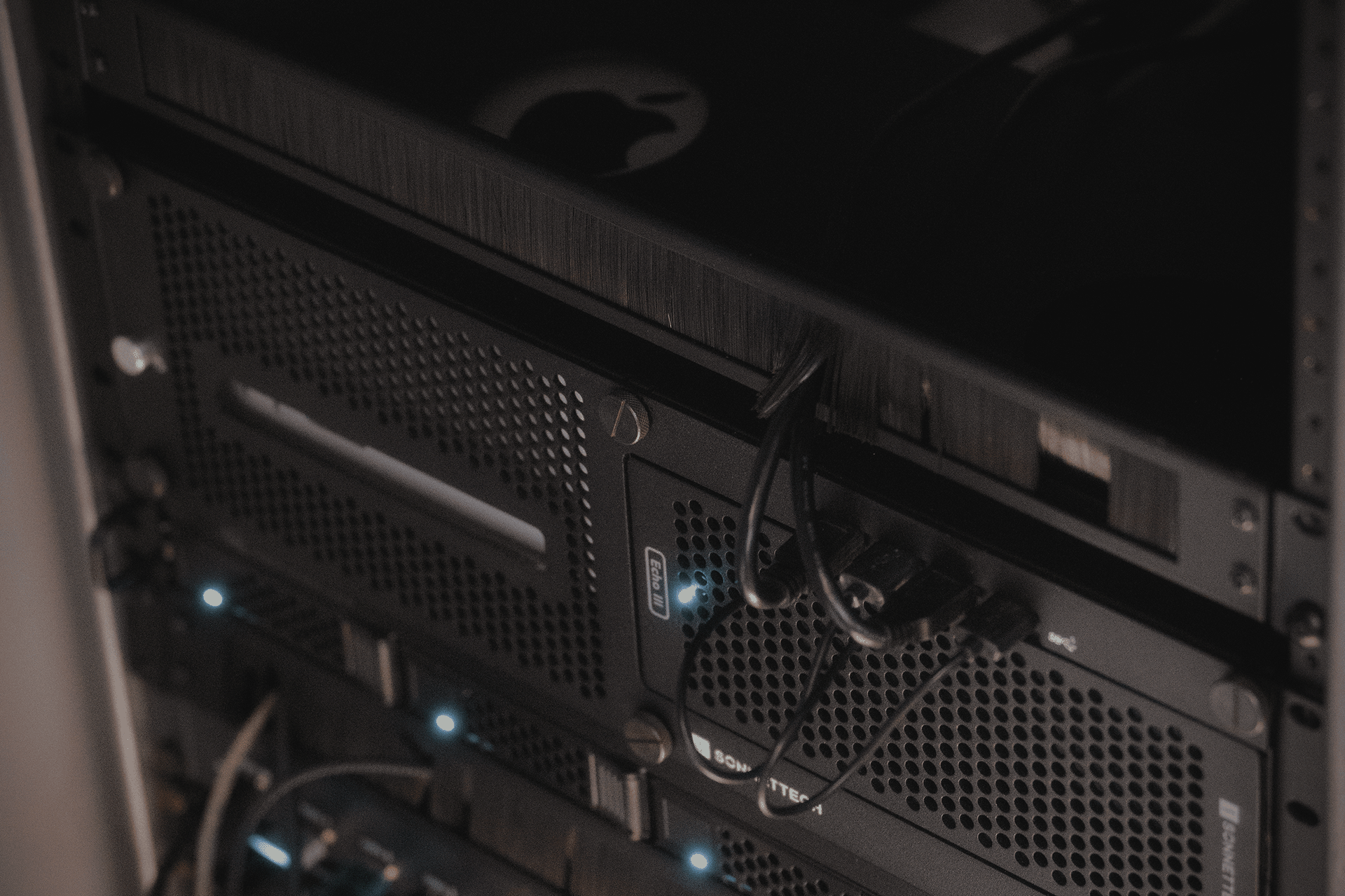 Close-up view of a Mac Studio computer mounted in a server rack with visible cables.