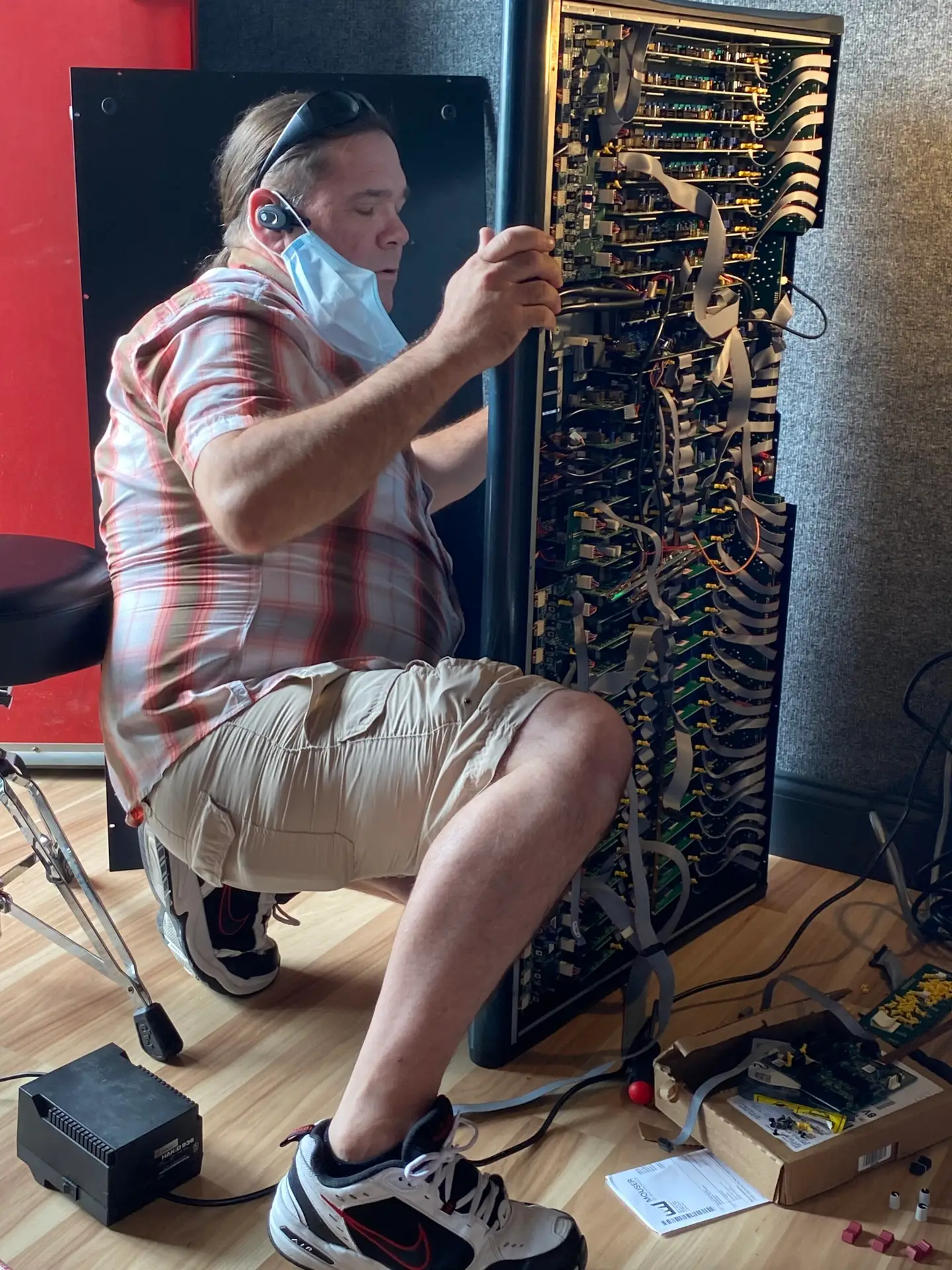 Individual adjusting a large electronic device with numerous wires and components in a studio setting.