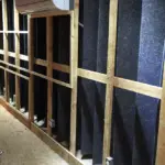 Interior view of a construction site featuring wooden framing and acoustic panels on the walls.