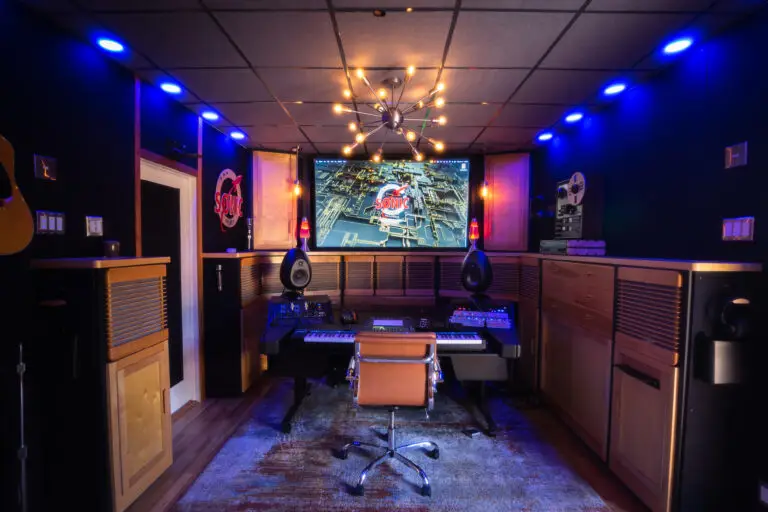 Interior of a home music studio featuring a keyboard, speakers, and a large screen display.