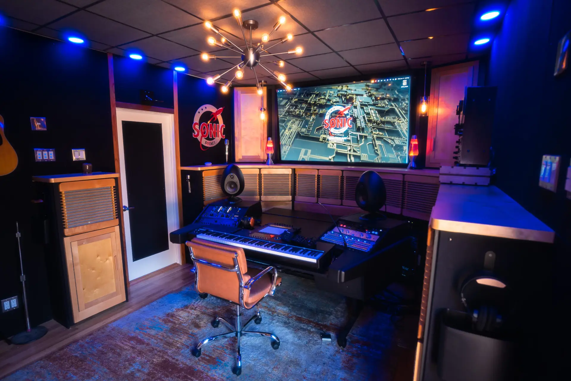 Interior view of a home recording studio featuring digital audio equipment and a large screen.