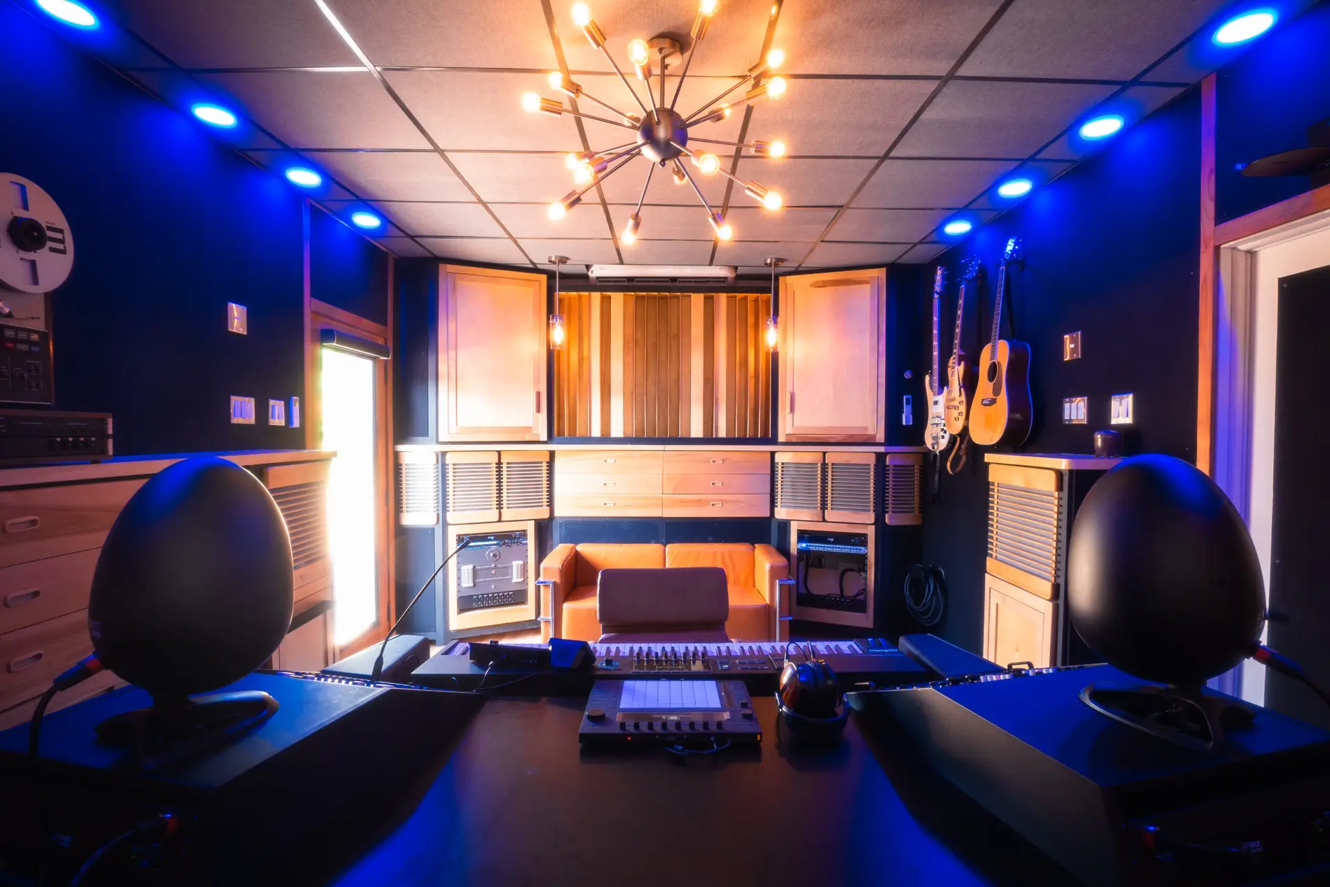 Interior view of a music recording studio featuring sound equipment and guitars on the wall.