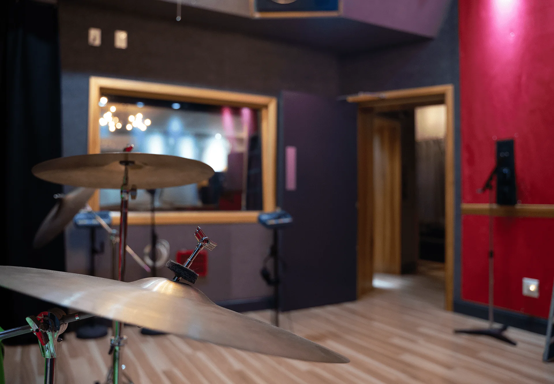 Sonic Studio live room with drum cymbals, red acoustic walls and the window into the control room