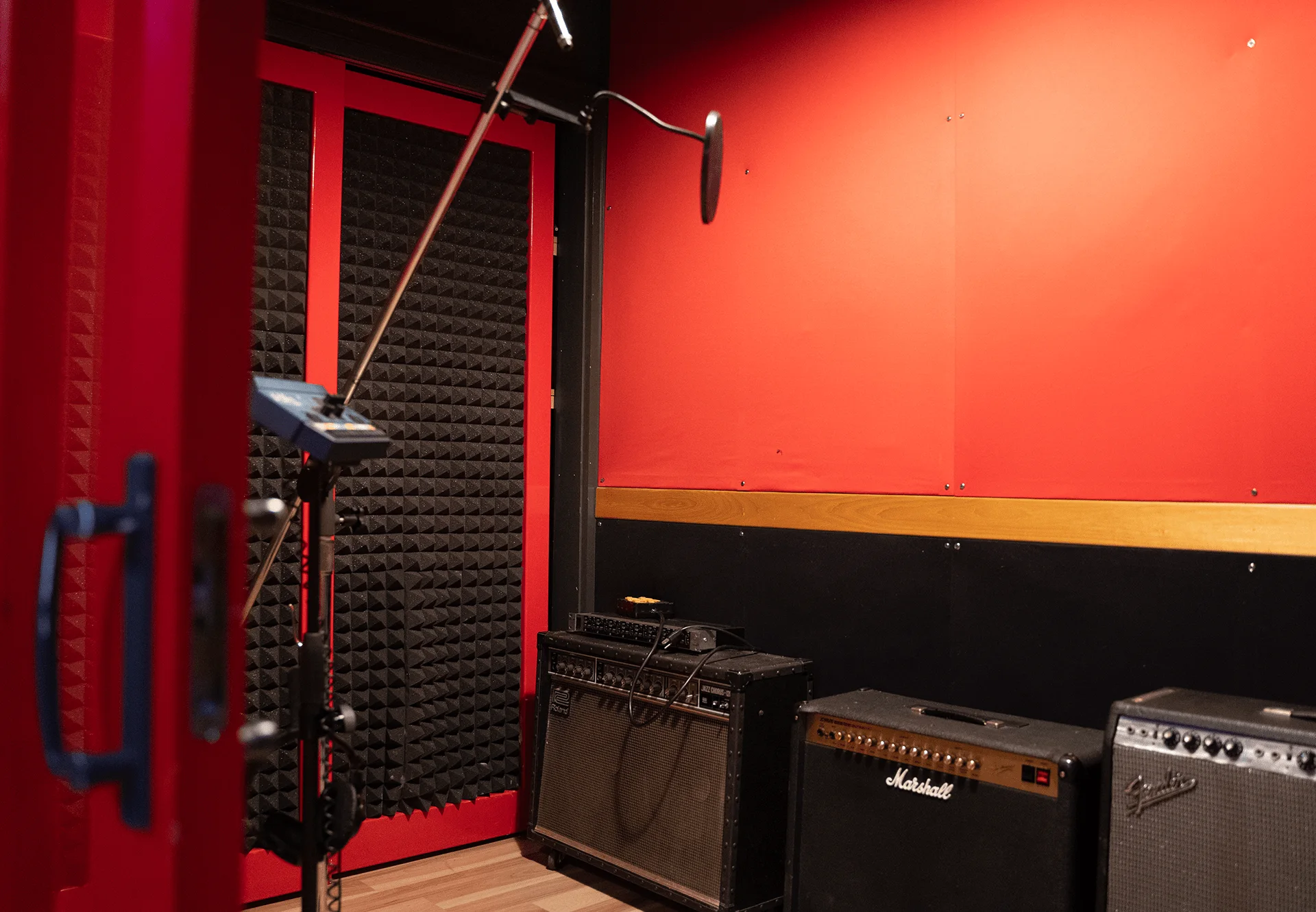 Red-walled live room at Sonic-Rocket with Marshall and Fender amps and a boom mic stand